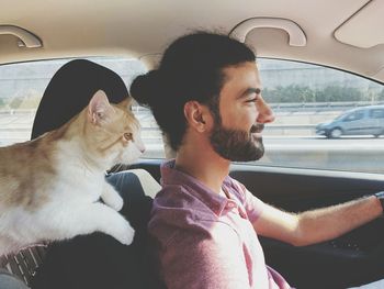 Smiling man with cat sitting in car