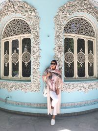 Woman wearing headscarf while leaning on wall