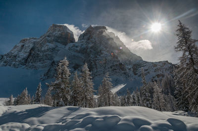 Scenic view of snow covered mountains against bright sun