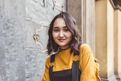 Portrait of young woman standing against wall