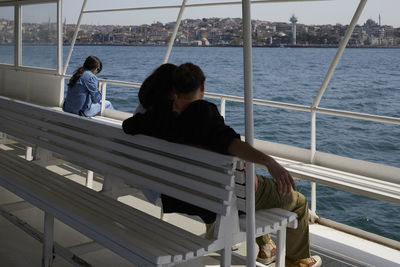 Rear view of man sitting on railing