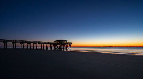 Pier over sea against clear sky during sunset