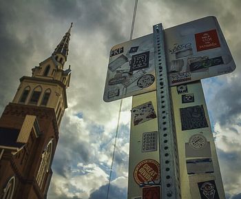 Low angle view of sign board against cloudy sky