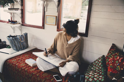 Woman sitting on book at home