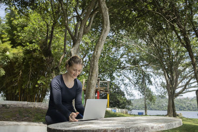 Young woman using a laptop at day time at a green park. mobile phone, technology,