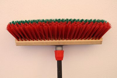 Close-up of red broom against wall