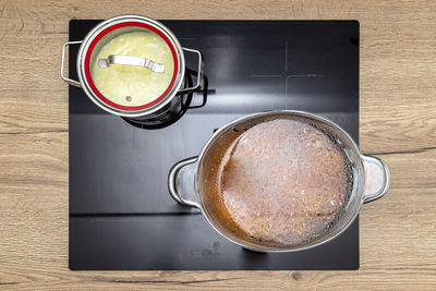 Steel pots with a cooking dish on an induction cooker built into the kitchen worktop on the cabinet