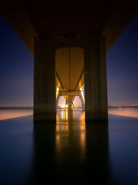 Illuminated bridge over sea against sky during sunset