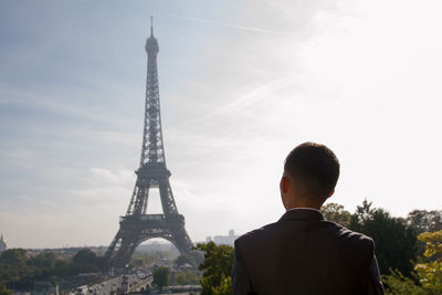 Rear view of businessman looking at eiffel tower against sky