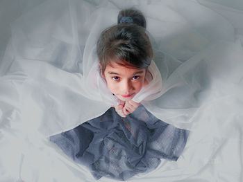 High angle portrait of girl sitting on bed