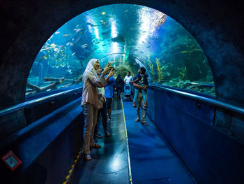 Rear view of people standing in illuminated tunnel