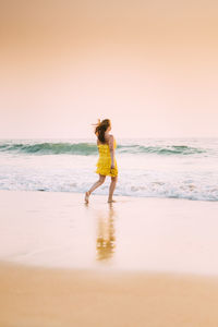 Rear view of woman standing at beach