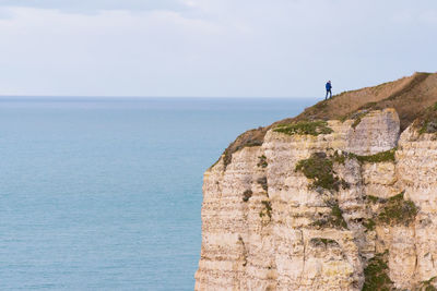 Scenic view of sea by mountain against sky