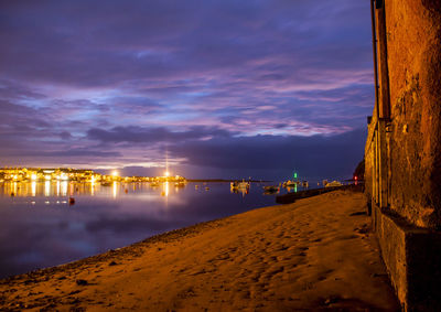 Scenic view of beach against cloudy sky at dusk