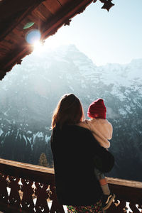 Rear view of woman standing on snowcapped mountain