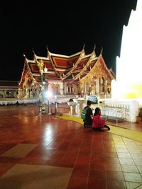 People at illuminated temple at night
