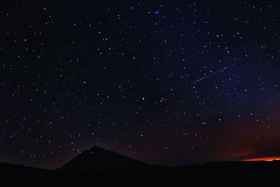 Low angle view of silhouette mountain against sky at night