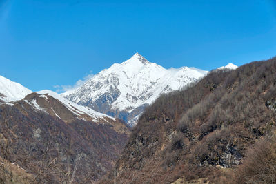 Scenic view of snowcapped mountains against clear blue sky