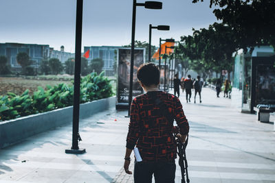 Rear view of boy walking on street in city