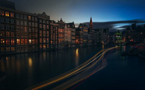 Light trails on road against buildings