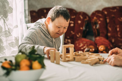 An elderly woman with down syndrome builds towers of their wooden toy blocks