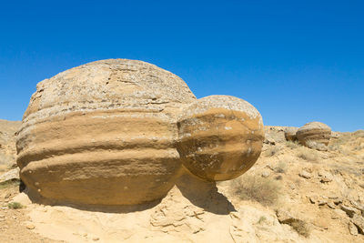 Low angle view of rock formations against clear blue sky