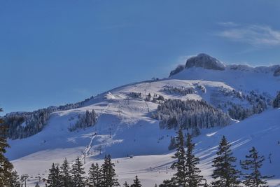 Scenic view of snow covered mountains against blue sky