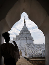 Rear view of man standing outside temple against building