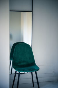 Empty chairs and table against wall in building