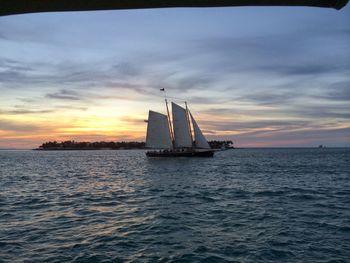 Sailboat sailing on sea against sky during sunset