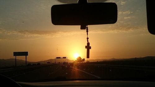 Road seen through car windshield during sunset