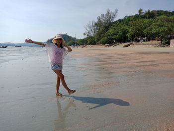 Portrait of woman with arm outstretched standing at beach