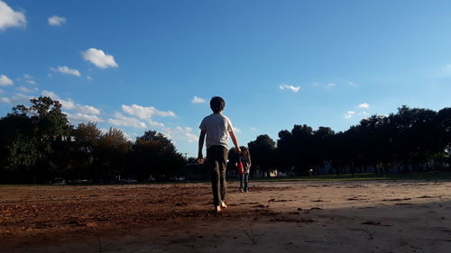 Rear view of man on field against sky