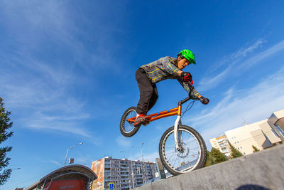 Low angle view of man performing bicycle stunt against sky