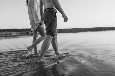 Low section of woman walking at beach against sky