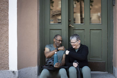 Smiling senior couple doing fist bump against doorway of house