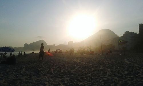 People on beach against clear sky during sunny day