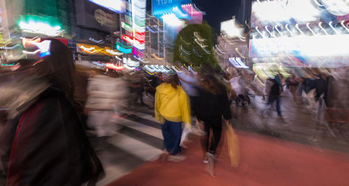 People walking on illuminated street at night