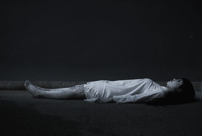 Side view of man sleeping against black background