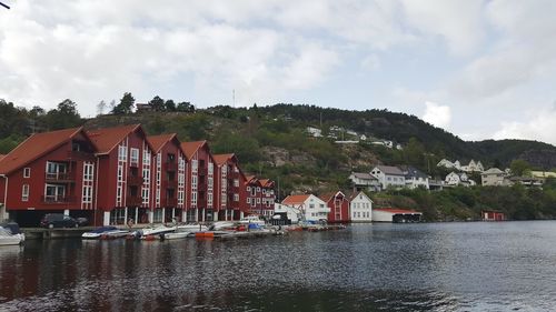 Buildings by river against sky