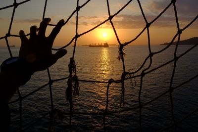 Silhouette people on sea against sky during sunset