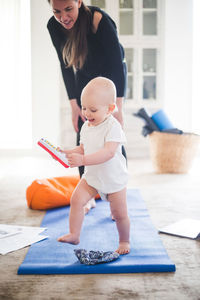 Female parent exercising on exercise mat while daughter playing with toy at home