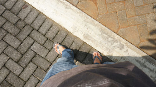 Low section of man standing on cobblestone street