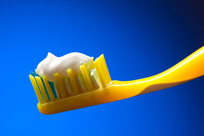 Close-up of toothpaste on toothbrush against blue background