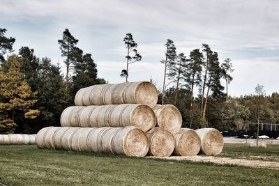 Stack of hay bales on field against sky