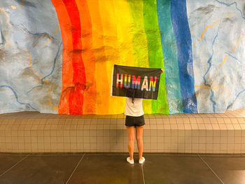 Rear view of woman against graffiti wall