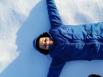 Portrait of young man lying down against blue wall