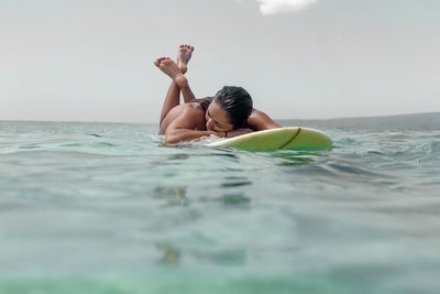 Woman lying on surfboard