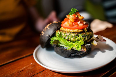 Broccoli quinoa charcoal burger topped with guacamole, mango salsa and fresh salad.