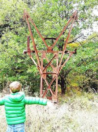 Rear view of boy on plants against trees